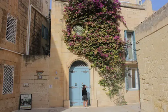 Honey colored house in Mdina with light blue door and pink flowers